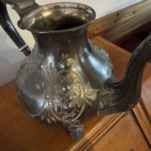 Ornate silver-plated teapot with repoussé floral decoration.