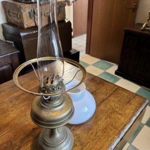 Antique Victorian brass hurricane lamp with white shade and clear flue.